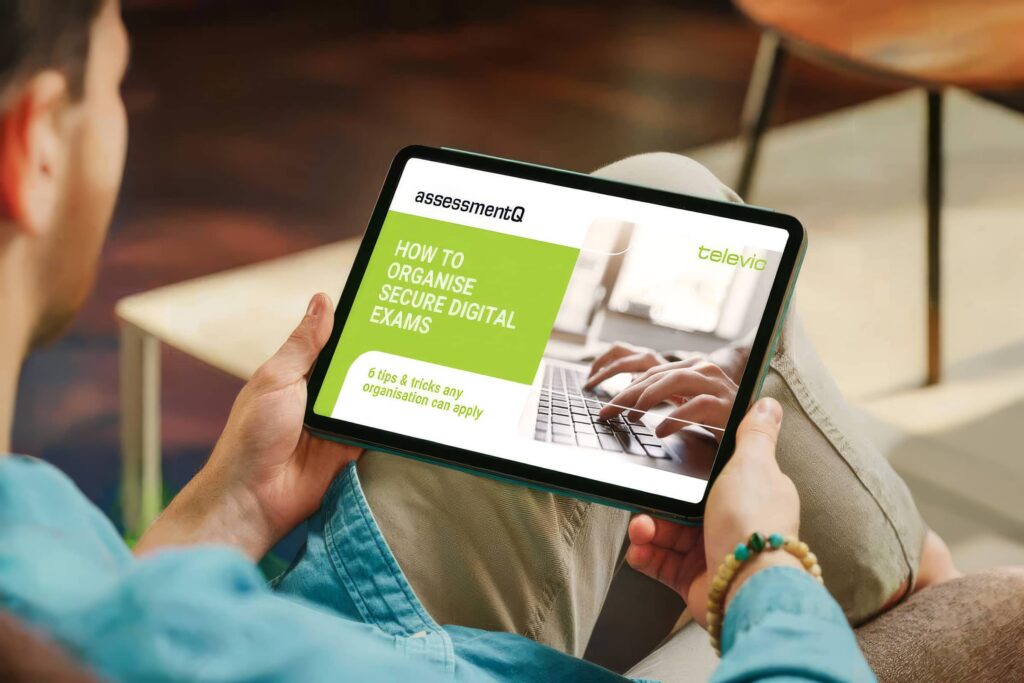 A tablet being held displaying the cover of an AssessmentQ and Televic whitepaper titled "How to Organise Secure Digital Exams" with the subtitle "6 tips & tricks any organisation can apply."