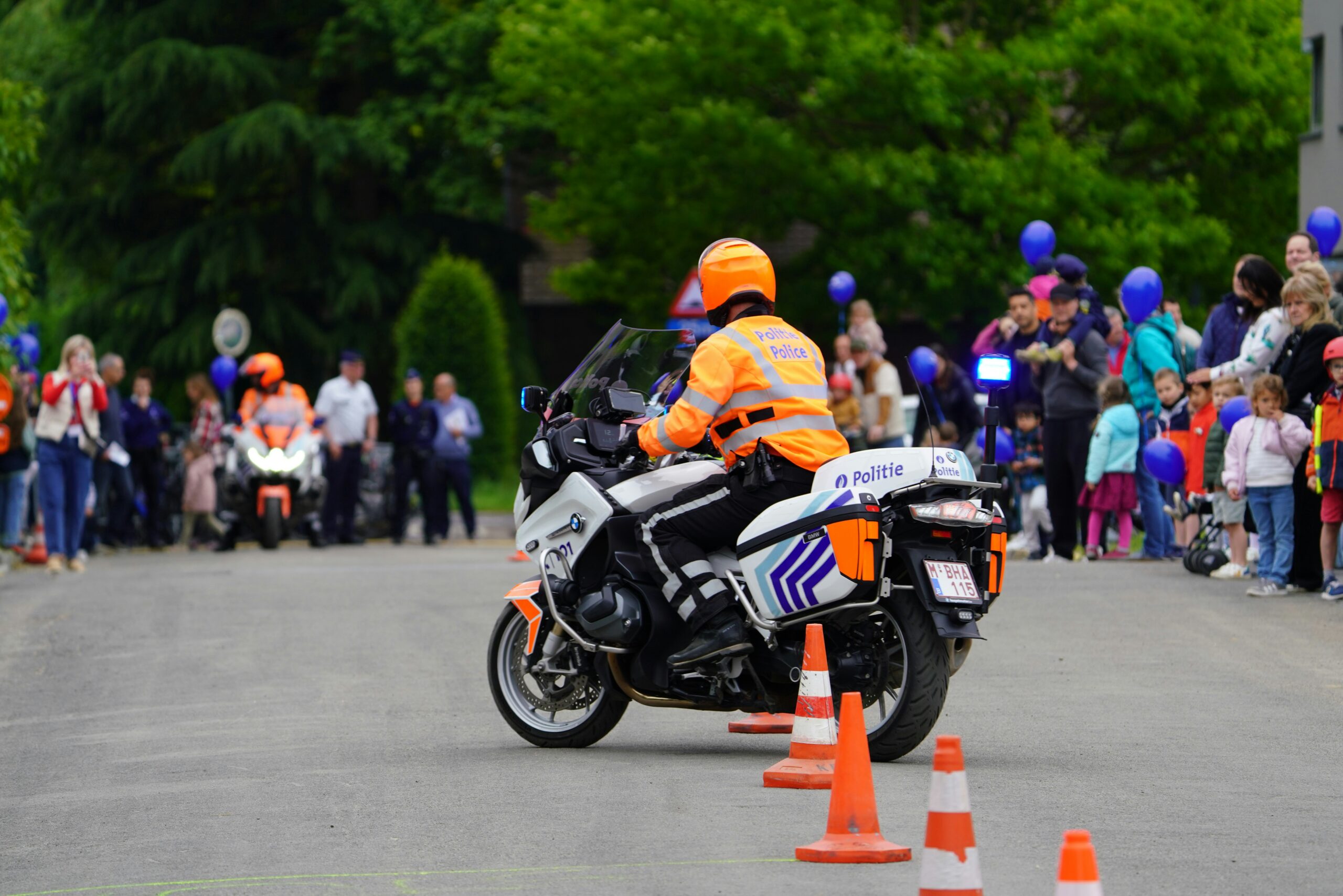 Police motorcyclist navigates a cone slalom during a public safety demonstration, showcasing precision riding skills for onlookers of all ages.